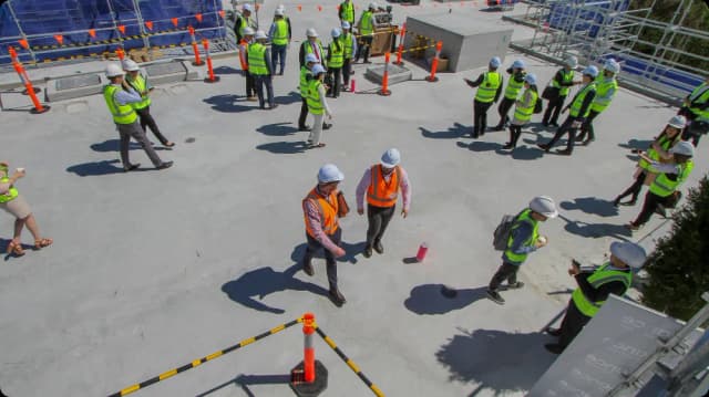 Construction site personnel wearing essential personal protective equipment (PPE), including hard hats and reflective safety vests.